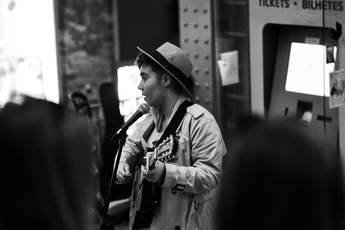 A guitarist performing outside on a Lisbon street, in black and white