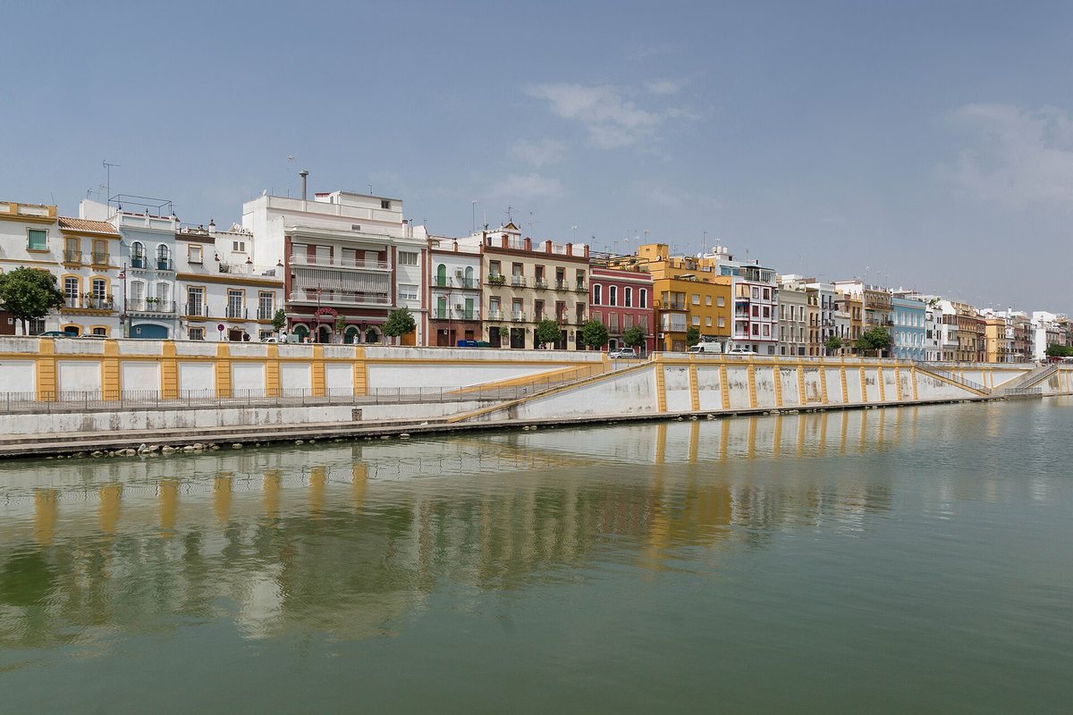 The Triana riverfront reflected in the water in Seville