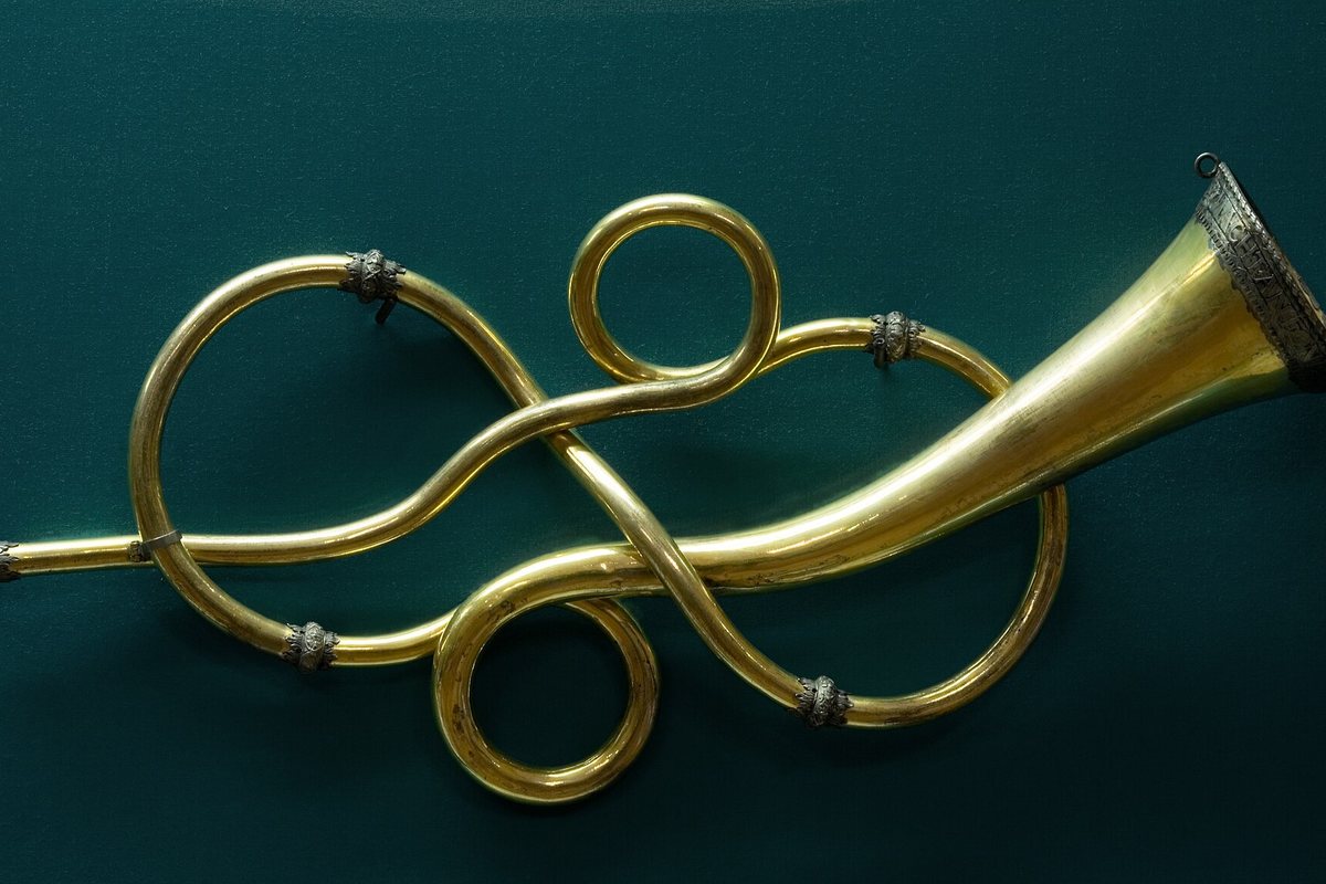 A historic brass trumpet displayed against a dark background