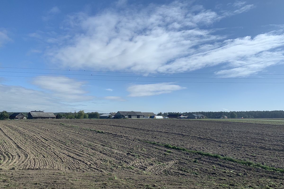 Fields and distant buildings in central Poland seen from a train