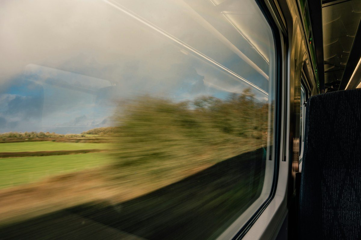 The countryside blurs outside a moving train window