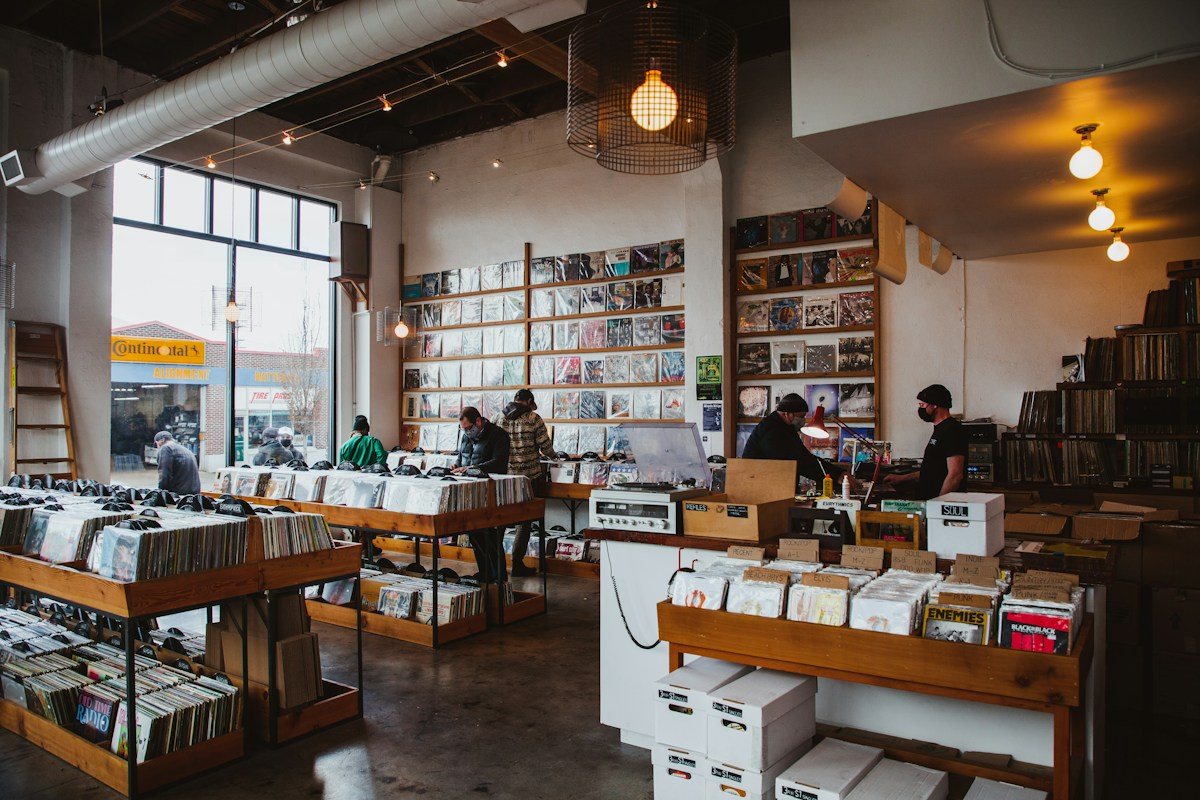 Warm pendant lights above tables of records in a music store