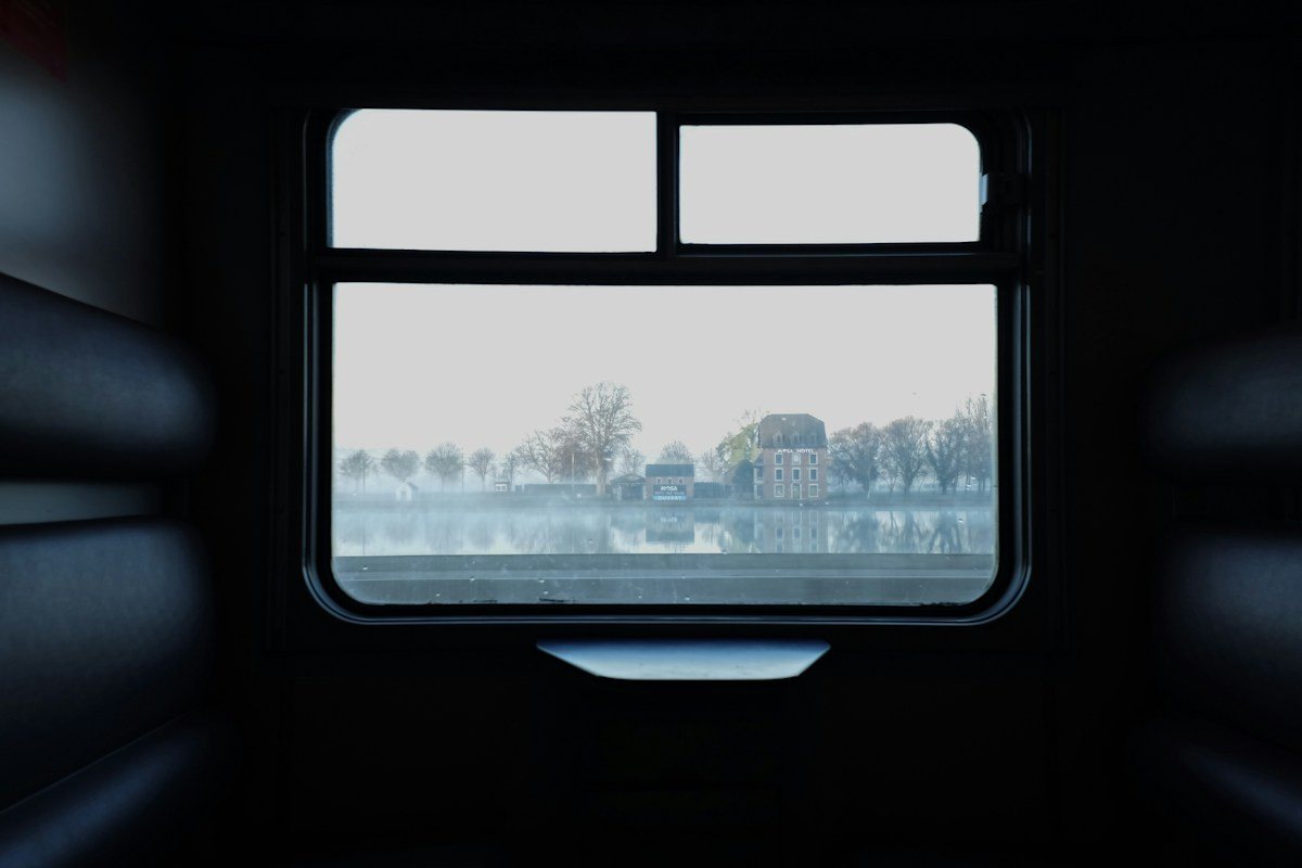 A pale landscape framed by a dark train window