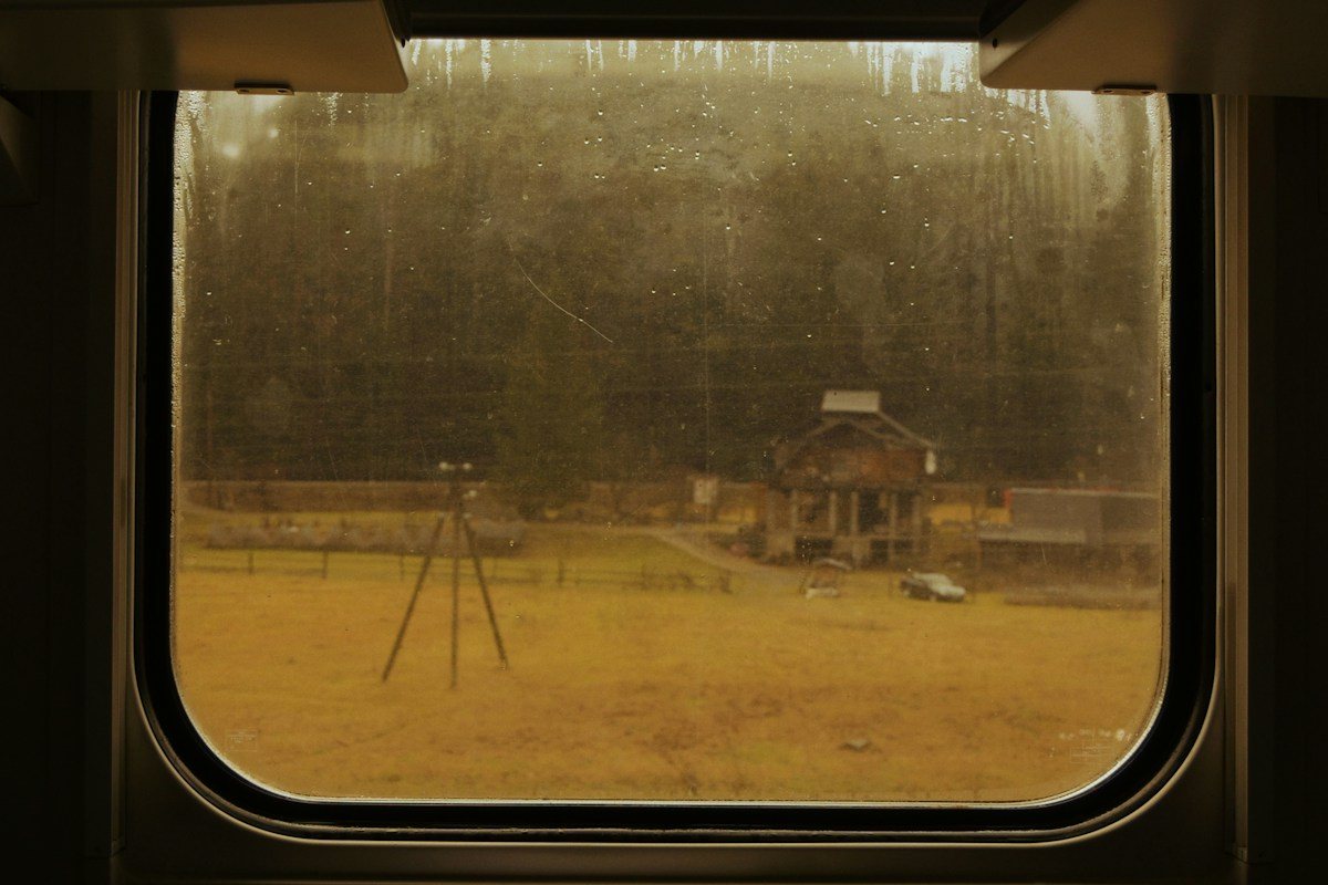 A rural landscape seen through an amber-tinted train window