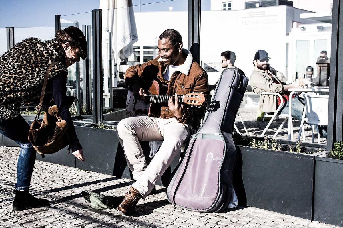 Guitarists perform beside an open instrument case in Lisbon