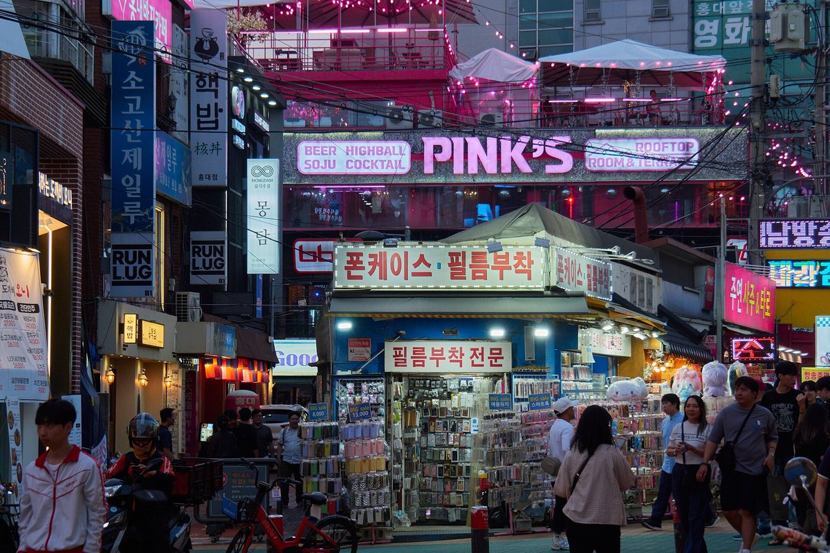 Neon storefront signs and pedestrians in Hongdae, Seoul, at night